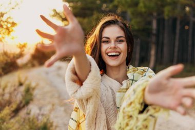 Ormanda bir yolda mutlu bir kadın elleriyle işaret ediyor ve gülüyor.