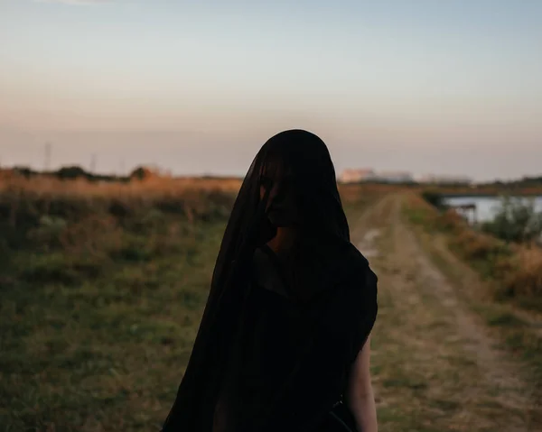 Egy nő fekete ruhában a fején kint a folyó mellett. — Stock Fotó