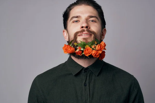 Elegant man with flowers in a beard,  decoration, studio background. High quality photo