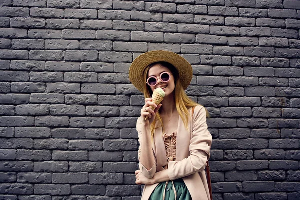 Glada kvinna i solglasögon med glass i händerna utomhus svart tegel vägg gata stil — Stockfoto
