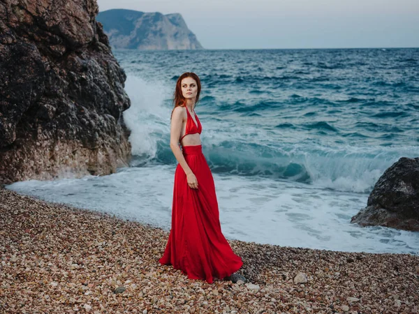 Όμορφη γυναίκα με κόκκινο φόρεμα στο νησί δίπλα στη θάλασσα — Φωτογραφία Αρχείου
