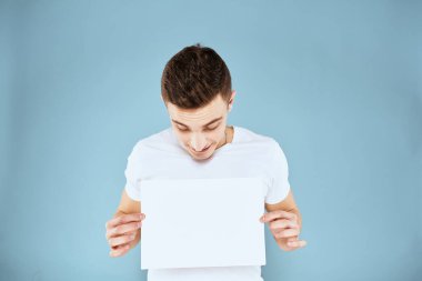 Beyaz tişörtlü bir adam kağıt fotokopi alanı tutuyor.