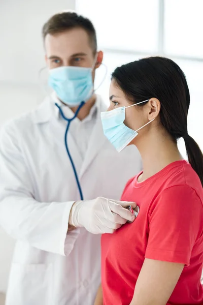 청진기를 가지고 있는 의사는 폐를 호흡하는 의료 마스크를 쓰고 있는 환자를 검사 한다 — 스톡 사진