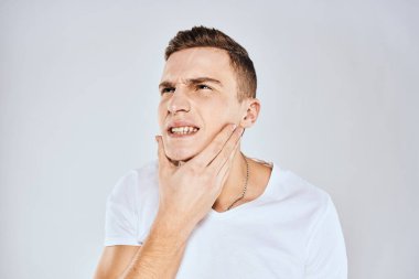 Beyaz tişörtlü duygusal bir adam elini arka planda tutuyor.