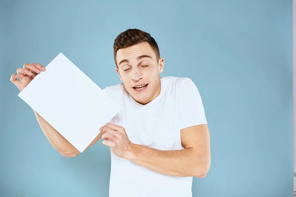 Een man in een wit t-shirt heeft een vel papier kopieerruimte — Stockfoto