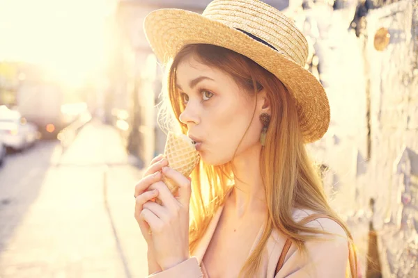 Веселая женщина в шляпе ест мороженое ходить под открытым небом солнце — стоковое фото