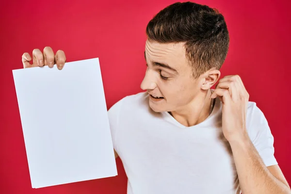 Emotionele man met een vel papier kopieerruimte t-shirt rode achtergrond — Stockfoto