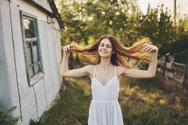 Mulher feliz em um vestido de verão branco perto do edifício na natureza e árvores no fundo — Fotografia de Stock