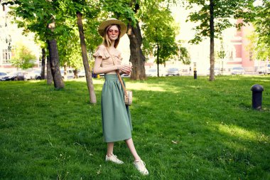 Şapkalı güzel bir kadın yaz parkında gezer.