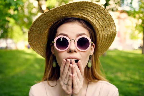 Glada kvinna i hatt bär solglasögon utomhus i parken gräs promenad — Stockfoto