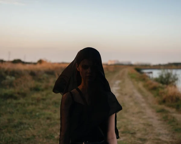 Egy nő fekete ruhában a fején kint a folyó mellett. — Stock Fotó