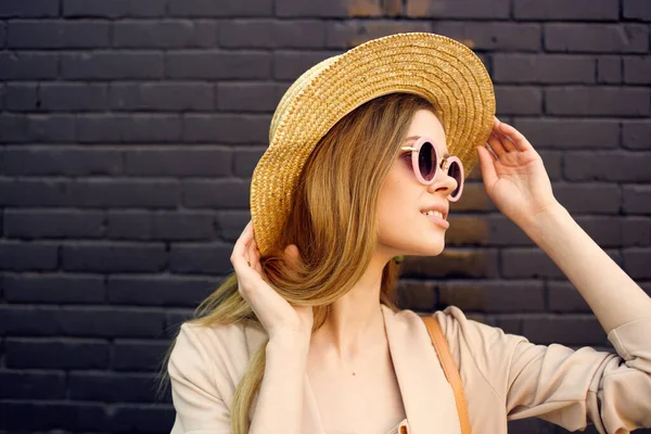 Ładna kobieta w kapeluszu w okularach przeciwsłonecznych na zewnątrz w mieście mur z cegły — Zdjęcie stockowe
