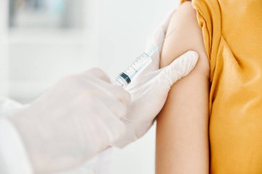 Bir doktor bir kadının omzuna kovid 19 aşısı enjekte ediyor.