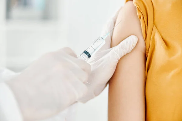 En läkare injicerar ett covid-19 vaccin i en kvinnlig skuldra — Stockfoto