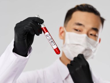 Siyah eldivenli Asyalı adam. Kan testi yakından inceleniyor. 