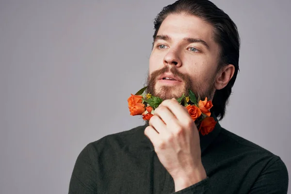 Elegant man with flowers in a beard,  decoration, studio background. High quality photo