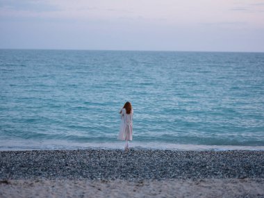 Okyanus kıyısındaki sahildeki kadın şeffaf süveter modeli.