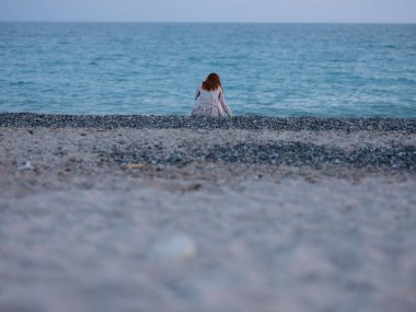 Okyanusun kıyısında beyaz pantolonlu bir kadın.