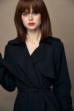 Seksi esmer, siyah ceketli, çekici görünüşlü, gülen. 