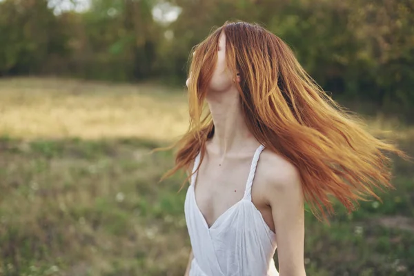 Gelukkig vrouwen in een sundress loopt op groen gras in de weide en bomen op de achtergrond — Stockfoto