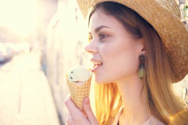 Elinde dondurma olan bir kadın güneşli bir günde şehirde dolaşıyor.