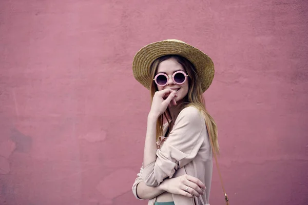 Pretty woman in sunglasses walk the pink wall outdoors