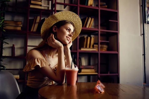 Una mujer se sienta en un café en un vaso de mesa con una bebida relajante mirada pensativa — Foto de Stock