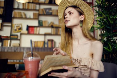 Şapkalı güzel bir kadın, elinde kitapla kafede tatil okuyor.