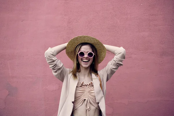Femme émotionnelle en chapeau marchant en plein air dans la ville sur fond de mur rose — Photo