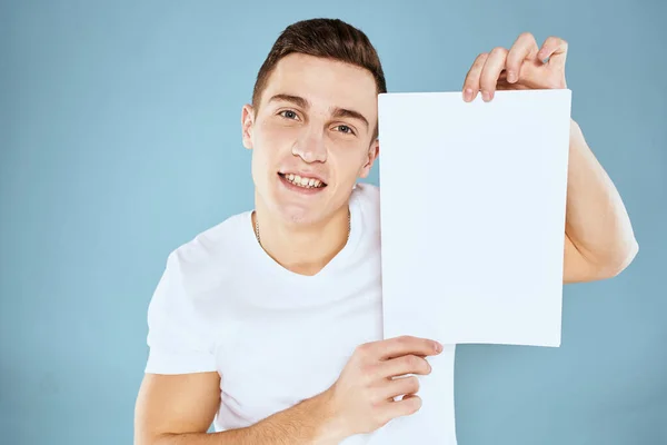 Un homme en t-shirt blanc tient une feuille d'espace de copie papier — Photo