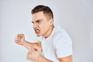 Duygusal adam elleri ile jestler hoşnutsuz beyaz tişört ışıklı arka plan