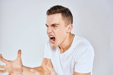 Duygusal adam elleri ile jestler hoşnutsuz beyaz tişört ışıklı arka plan