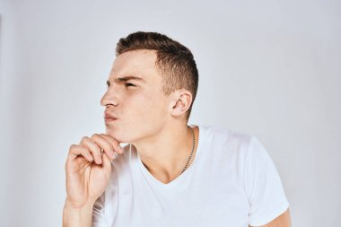 Beyaz tişörtlü duygusal bir adam elini arka planda tutuyor.