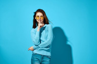 Mavi kazaklı güzel bir kadın. Sarı güneş gözlüklü. Gülümsüyor.