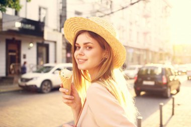 Güzel bir kadın, elinde dondurmayla şehirde dolaşıyor.