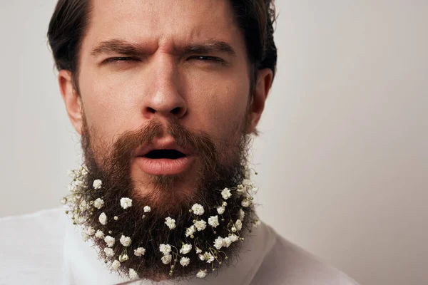 Emotional man with beard flowers white shirt studio close-up