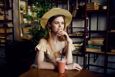 Bir kadın kahve bardağında oturup içki içerken düşünceli bir bakışla rahatlıyor.