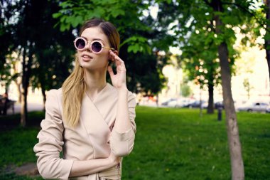 Yeşil ağaçların arasında güneş gözlüklü güzel bir kadın seyahat ediyor.