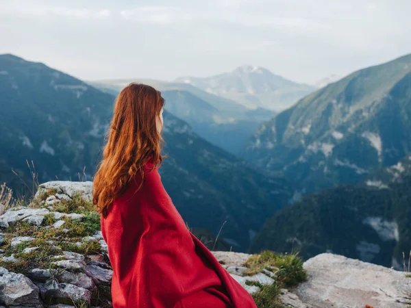 산 속에서 붉은 담요로 덮인 돌 위에 앉아 있는 여자 — 스톡 사진