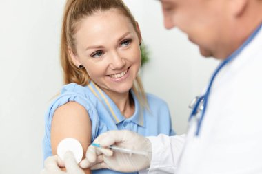 Erkek doktor, el sağlığı hastasına covid aşısı yapıyor.