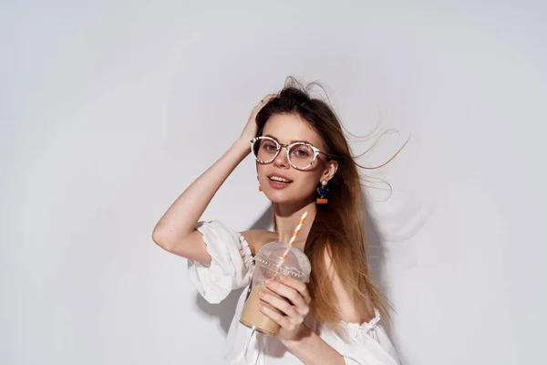 Jolie femme lunettes à la mode décoration sourire verre avec boisson charme fond clair — Photo