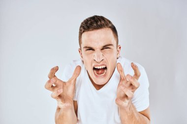 Duygusal adam elleri ile jestler hoşnutsuz beyaz tişört ışıklı arka plan