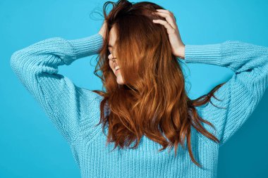 Mavi kazak içinde güzel bir kadın. Çekici görünüyor. Yakından poz veriyor.