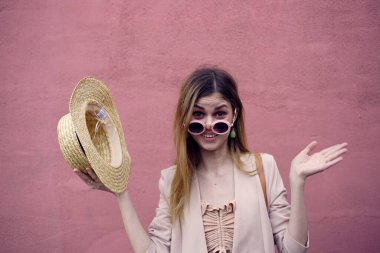 Şapkalı neşeli kadın şehir tarzı pembe duvarda yürüyor.