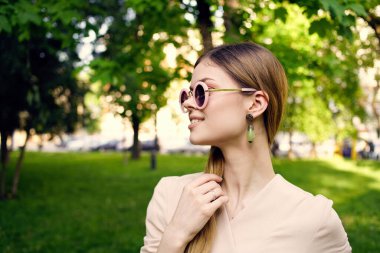 Güneş gözlüğü takan güzel bir kadın yeşil çimen manzaralı temiz hava.