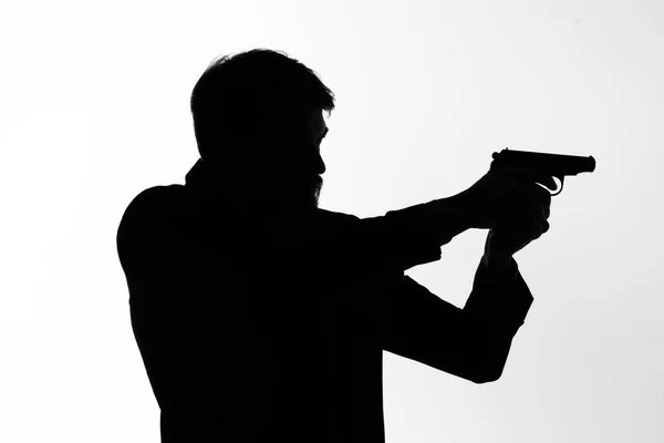 Sombra de un hombre con un arma en sus manos apuntando al fondo de la luz del crimen detective — Foto de Stock