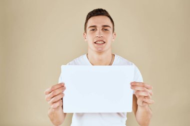 Beyaz t-shirt kağıtlı adam ellerinde Boşluk kırpılmış bej arkaplanı kopyala