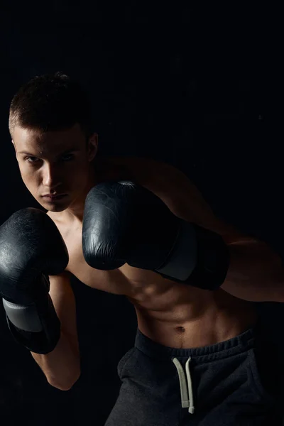 Sportovec v černé boxerské rukavice na tmavém pozadí kulturista fitness — Stock fotografie
