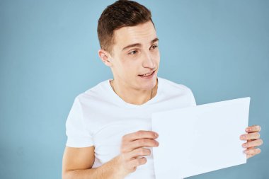 Beyaz tişörtlü bir adam kağıt fotokopi alanı tutuyor.