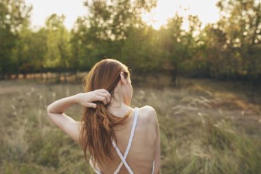 Doğada ve yaz ağaçlarında çayırlarda bir kadın tatil modeli güneş